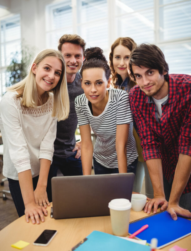 Group of business executives smiling at camera at their desk in the office